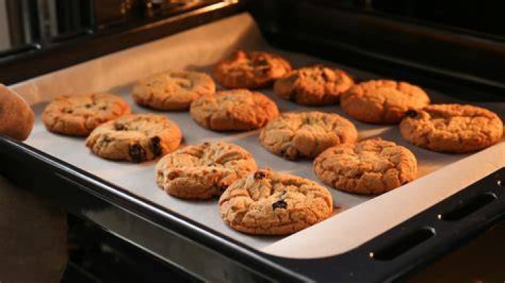 Baking sheet with chocolate cookies, peanut butter chips, and a spoonful of peanut butter