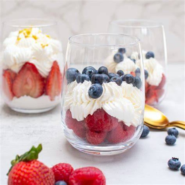 Berries, whipped cream, and caramelized sugar in a white baking dish.