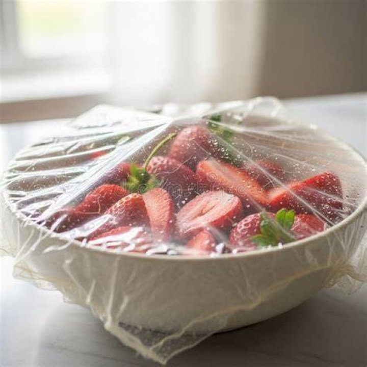 Bowl of sliced strawberries covered in jam.