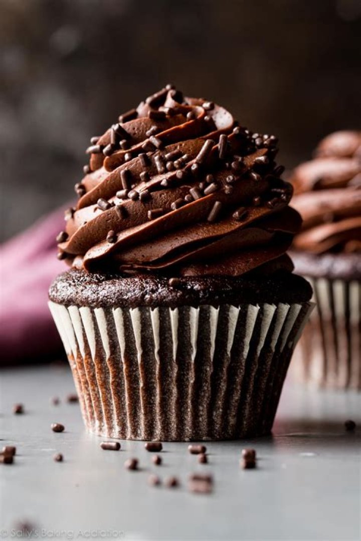 Chocolate cupcake topped with a chocolate dipped strawberry on a white plate. 