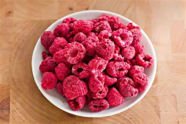 Freeze dried raspberries in a bag and in a white bowl.