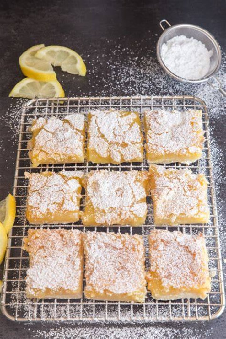 Lemon bars on a rack garnished with whipped cream and a lemon slice.