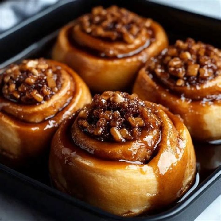Unbaked sticky buns in a round baking pan with pecans.
